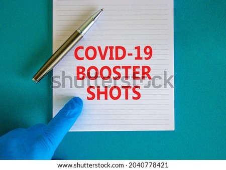 Covid-19 booster shots vaccine symbol. White note with words Covid-19 booster shots, beautiful blue background, doctor hand and metallic pen. Covid-19 booster shots vaccine concept.
