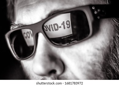 COVID-19 In Computer Screen Reflects In Man Glasses. Person Watching Corona Virus News In TV In Dark. Concept Of Coronavirus, Social Media, Cyber, Hacker, Panic, Network And Web Work Due To Pandemic.