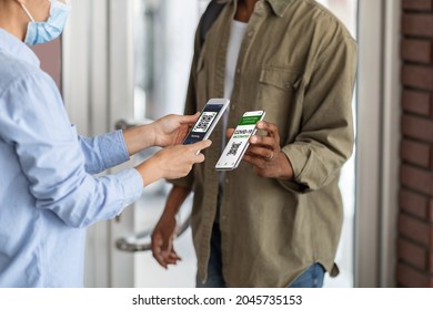 Covid-19 Control. Female Worker Scanning Health Qr Code Of Black Male Visitor On Entrance To Public Place, Unrecognizable African Man Demonstrating Digital Vaccination Certificate On Smartphone - Shutterstock ID 2045735153