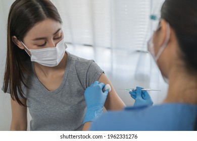 Covid-19, Coronavirus Asian Young Woman Getting Vaccine From Doctor Or Nurse Giving Syringe Shot To Arm's Patient. Vaccination, Immunization, Disease Prevention Against Flu Or Virus Pandemic Concept.