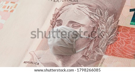 COVID-19, the coronavirus in Brazil. Brazilian effigy of republic symbol at the ten real banknote with face mask. 10 real brl. Concept of impacts to the economy, crisis and finance.