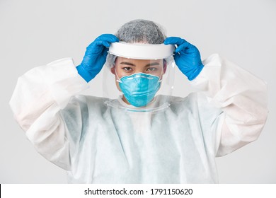 Covid-19, Coronavirus Disease, Healthcare Workers Concept. Confident Serious-looking Asian Female Doctor, Put On Face Shield And Personal Protective Equipment Before Entering Contagious Zone