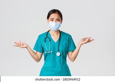 Covid-19, Coronavirus Disease, Healthcare Workers Concept. Troubled And Confused Asian Female Nurse In Scrubs And Medical Mask Asking Question, Shrugging And Look Concerned, White Background