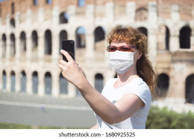 COVID-19 Coronavirus In Europe, Woman Wearing Face Mask Makes Selfie By Empty Coliseum, Rome, Italy. Tourist Landmarks Closed Due To Pandemic. Concept Of Travel, Lockdown And COVID Quarantine.