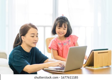 Covid-19 Coronavirus And Learning From Home, Home School Kid Concept.Little Asian Girl Study With Online Learning And Asian Mother Work From Home With Laptop.Quarantine And Social Distancing Concept.