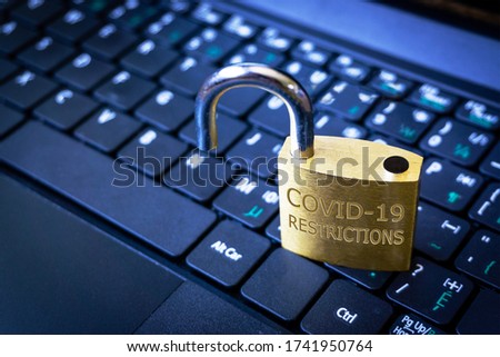 COVID-19 coronavirus lockdown restrictions ease concept illustrated by unlocked padlock on laptop.