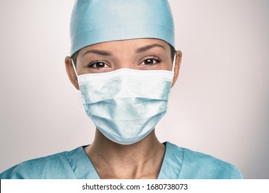 COVID-19 Coronavirus pandemic happy Asian doctor positive with hope wearing surgical mask and blue protective scrubs at hospital. Inspiring confidence in the future to solve the crisis.