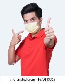 COVID-19 Coronavirus Portrait Handsome Young Asian 
Man Wearing Red Shirt And Mask Protection From Covid 19 And Thumbs Up Sign  Isolated On White Background In Studio. Asian People. COVID-19 Concept.