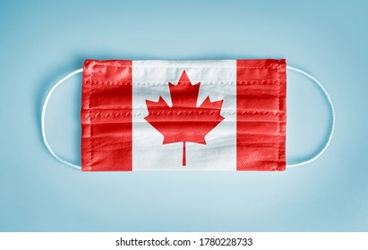 Covid-19 Coronavirus-Schutzkonzept: Medizinische Einwegmaske mit kanadischer Flagge auf blauem Hintergrund.   Soziale Distanzierung und Nutzung von Maske wichtig, um geschützt zu werden.