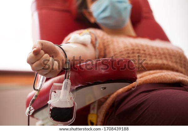 COVID-19 Coronavirus survivor patient donate\
convalescent PRP blood plasma, platelet rich AB plasma female donor\
sitting in chair,closeup bag filled in blood bank,SARS-CoV-2\
therapy treatment and\
cure