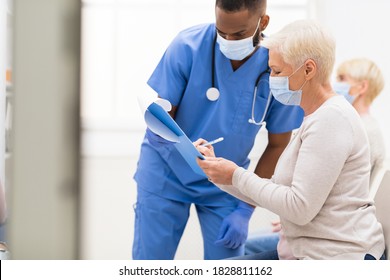 Covid-19, Coronavirus Vaccination. Senior Patient Woman Signing Papers With Doctor Before Corona Virus Vaccine Injection In Hospital Waiting-Room. Covid Medical Immunization Campaign Concept