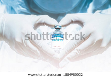 COVID-19 coronavirus vaccine with a vial in the hand wearing medical latex gloves form a heart shape. Virus destruction. Breakthrough in the creating and against coronavirus disease 2019 or COVID-19.