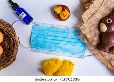 Covid19 Easter And Concept. Flat Lay With Face Mask And Covid Vaccine With Easter Symbols Like Easter Eggs And Chocolate Bunny