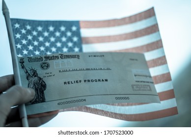 COVID-19 Economic Stimulus Check On Blurred USA Flag Background. Relief Program Concept. 