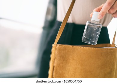 COVID-19 hand sanitizer woman using small sanitiser bottle in bag when going out walking to work in public for washing hands disinfecting with alcohol gel dispenser.