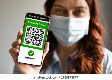 Covid-19 Health Passport. Traveler woman wearing a face mask holding a passport, ticket pass and smartphone with digital health passport app.