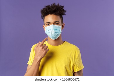 Covid19, Healthcare And Medicine Concept. Young Hispanic Guy With Afro Haircut, Wear And Point At Face Mask, Social-distancing During Pandemic, Explain Friends How To Prevent Catching Disease