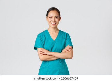 Covid-19, healthcare workers, pandemic concept. Confident smiling asian doctor, female nurse in scrubs standing determined, cross arms chest over white background. Doctor ready for shift in clinic - Powered by Shutterstock