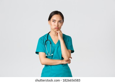 Covid-19, Healthcare Workers, Pandemic Concept. Annoyed And Bothered Asian Female Doctor, Nurse On Her Shift Looking Irritated Or Tired, Eye Roll Bored And Exhale, Standing White Background In Scrubs