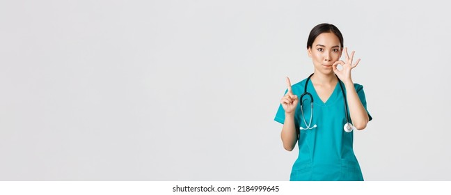 Covid-19, healthcare workers, pandemic concept. Serious-looking worried asian female nurse, physician asking keep secret, shaking finger and showing mouth seal, zipping lips gesture