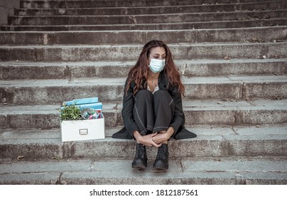 COVID-19 Lay Off And Unemployment. Depressed Business Woman With Face Mask Outside Office With Personal Staff Box Feeling Hopeless After Losing Job Due To Redundancy Amid Coronavirus Job Cuts.