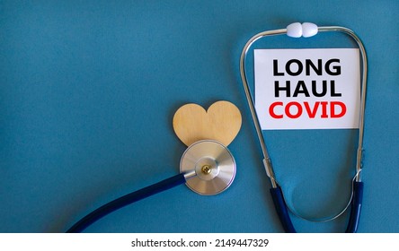 COVID-19 long-haul covid symptoms symbol. White card with words Long haul covid. Wooden heart, stethoscope, beautiful blue background, copy space. Medical, COVID-19 long-haul covid symptoms concept.