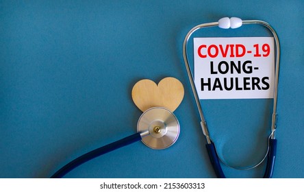 COVID-19 long-haulers covid symptoms symbol. White card with words Covid-19 long-haulers. Wooden heart, stethoscope, blue background, copy space. Medical, COVID-19 long-haulers covid symptoms concept.