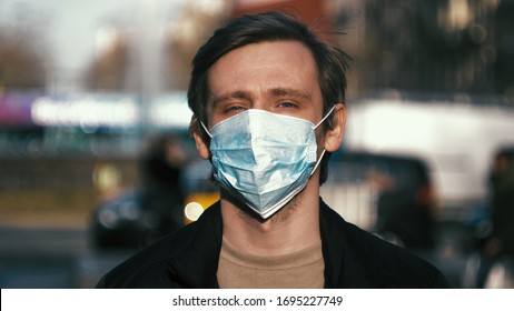 COVID-19 Man in city street wearing face mask protective for spreading of Coronavirus Disease in europe. Portrait of man with surgical mask on face against SARS-CoV-2.