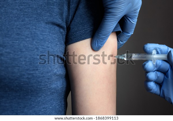 COVID-19 or monkeypox vaccine injection,\
doctor in gloves holds syringe and makes vaccine jab to woman\
patient arm. Concept of coronavirus, flu, vaccination, smallpox\
therapy, shot and\
treatment.