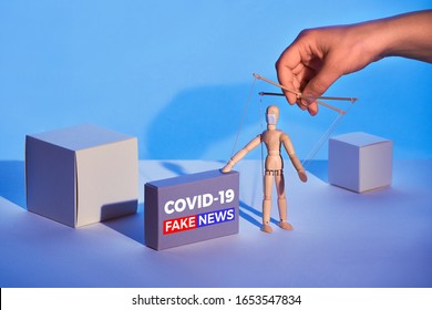 Covid19 novel coronavirus rumors. Sinister hand control wooden puppet on abstract geometric background. Box with text "COVID-19 fake news". Beware of fake news about outbreak 2019-nCoV and treatment