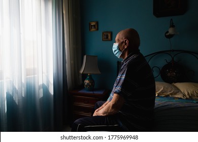 Covid-19 Old Man Sitting On His Bed Looking At The Window Wearing And Antivirus Mask 