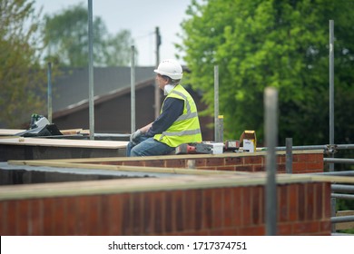 Covid-19 Outbreak. Construction Site Worker During Break Wearing White Helmet And Face Mask And Hi Vis Resting. Concept Of Break, No Duties, Depression, Job Loss, Unemployment. London, UK 28/04/2020