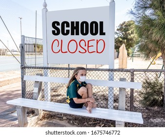 Covid-19 Outbreak Schools Closures. Sad And Bored Schoolgirl Kid With Face Mask Feeling Depressed And Lonely Outside Her Closed School. Restrictions And Lockdown As Coronavirus Containment Measures.