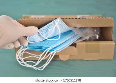 COVID-19 Package Of New Surgical Masks. Directly Above View Of PPE Medical Box Supplies For Healthcare Workers At Hospital. Woman Working In Coronavirus Pandemic Taking A Mask. Humanitarian Aid Help 