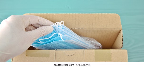 COVID-19 Package Of New Surgical Masks. Directly Above View Of PPE Medical Box Supplies For Healthcare Workers At Hospital. Woman Working In Coronavirus Pandemic Taking A Mask. Humanitarian Aid Help