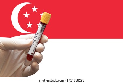 COVID-19 Pandemic Coronavirus Concept ; Close-up Of A Positive COVID-19 Blood Test Sample Tube With Flag Of Singapore At Background. Blood Testing For Diagnosis New Corona Virus Infection.