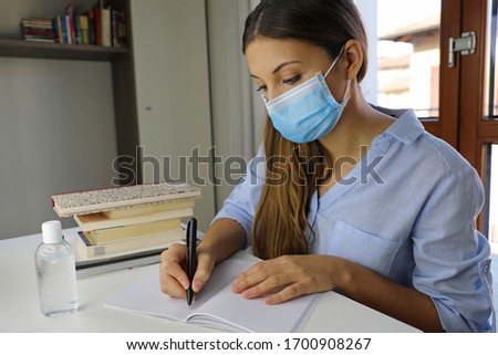 COVID-19 Pandemic Coronavirus Home Schooling Student Girl with Surgical Mask Working from Home. Distance learning quarantine young woman studying from home for virus disease 2019-nCoV.