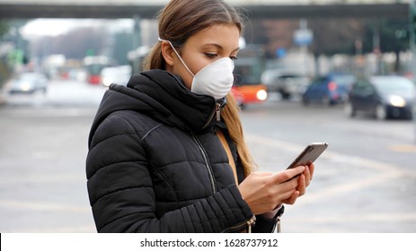 COVID-19 Pandemic Coronavirus Mobile Application - Young Woman Wearing Face Mask Using Smart Phone App In City Street To Aid Contact Tracing In Response To The 2019-20 Coronavirus Pandemic