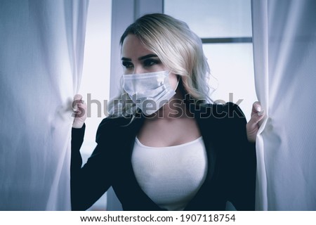 COVID-19 Pandemic Coronavirus Woman at home on quarantine wearing face mask protective for spreading of disease virus SARS-CoV-2. Girl isolation mask on face against Coronavirus Disease 2019. 