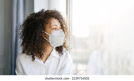 COVID-19 Pandemic Coronavirus. Young African american girl home isolation quarantine wearing face mask ffp2 protective for spreading of virus SARS-CoV-2                                         