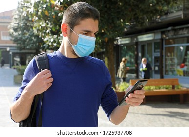 COVID-19 Pandemic Coronavirus Young Man Wearing Surgical Mask Using Smart Phone App in City Street to Aid Contact Tracing and Self Diagnostic in Response to the Coronavirus Pandemic 2019 - Shutterstock ID 1725937708