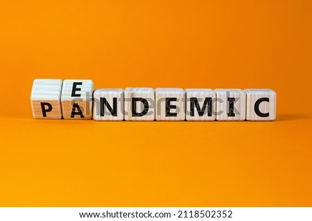 Covid-19 pandemic or endemic symbol. Turned wooden cubes and changed the concept word pandemic to endemic. Beautiful orange background copy space. Medical Covid-19 pandemic or endemic concept.