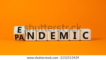 Covid-19 pandemic or endemic symbol. Turned wooden cubes and changed the concept word Pandemic to Endemic. Beautiful orange background copy space. Medical Covid-19 pandemic or endemic concept.