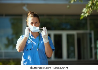 Covid-19 Pandemic. Modern Medical Doctor Woman In Scrubs With Stethoscope And Medical Mask Outside Near Clinic.