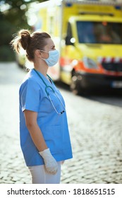 Covid-19 Pandemic. Modern Medical Doctor Woman In Uniform With Stethoscope And Medical Mask Outside Near Ambulance.