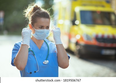 Covid-19 Pandemic. Modern Medical Doctor Woman In Uniform With Stethoscope And Medical Mask Outside Near Ambulance.