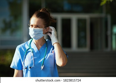 covid-19 pandemic. modern medical doctor woman in scrubs with stethoscope and medical mask outdoors near hospital.