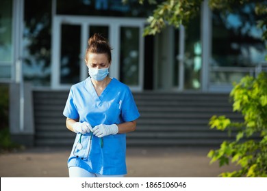 Covid-19 Pandemic. Tired Modern Medical Doctor Woman In Scrubs With Stethoscope And Medical Mask Outside Near Clinic.