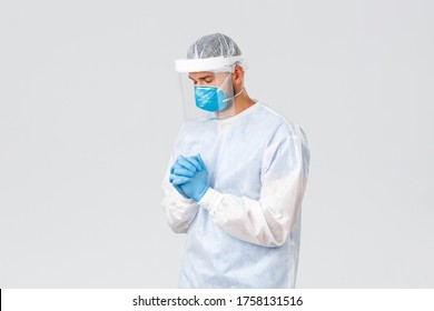 Covid-19 Pandemic, Virus Outbreak, Clinic And Healthcare Workers Concept. Hopeful Worried Doctor In Personal Protective Equipment, Close Eyes And Pray, Pleading God Treat Coronavirus