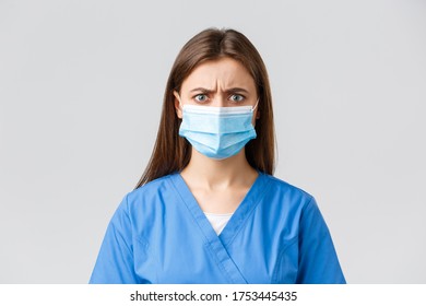 Covid-19, Preventing Virus, Health, Healthcare Workers And Quarantine Concept. Angry Or Frustrated Female Nurse Reacting To Bad News. Doctor In Blue Scrubs And Medical Mask Frowning Disappointed